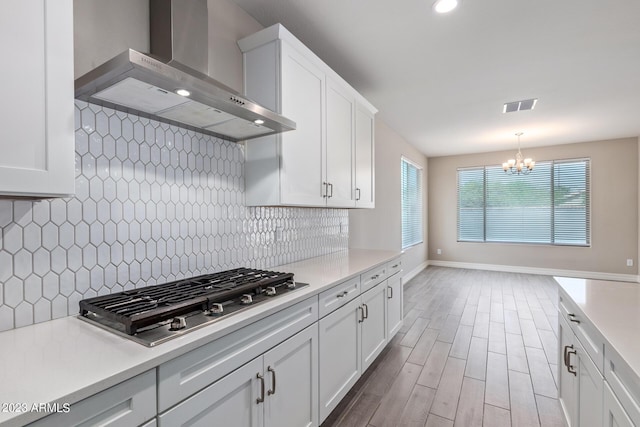 kitchen with white cabinets, a wealth of natural light, wall chimney exhaust hood, and stainless steel gas cooktop