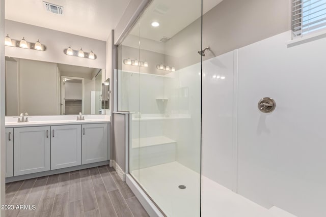 bathroom with wood-type flooring, vanity, and a shower with door