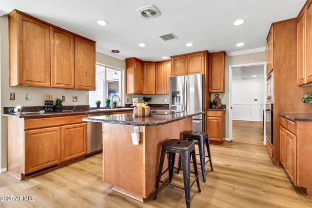 737 E 7th Pl, Mesa, AZ 85203 - kitchen featuring appliances with stainless steel finishes, ornamental molding, a kitchen island, brown cabinets, and recessed lighting