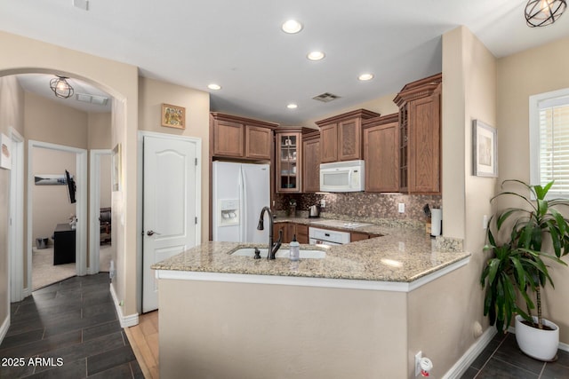 5612 S 21st Pl, Phoenix, AZ 85040 - kitchen with white appliances, a sink, brown cabinets, a peninsula, and arched walkways