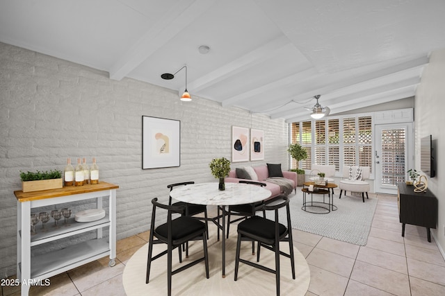 dining room featuring light tile patterned floors, lofted ceiling with beams, brick wall, and a ceiling fan