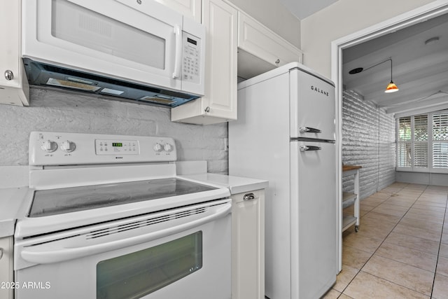 kitchen with tasteful backsplash, light countertops, light tile patterned flooring, white cabinets, and white appliances