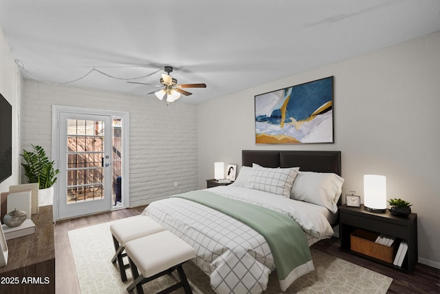 bedroom with ceiling fan, wood finished floors, and brick wall