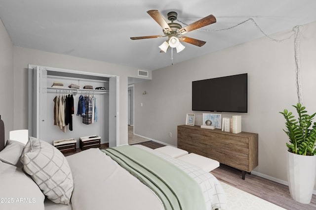 bedroom with visible vents, baseboards, ceiling fan, wood finished floors, and a closet