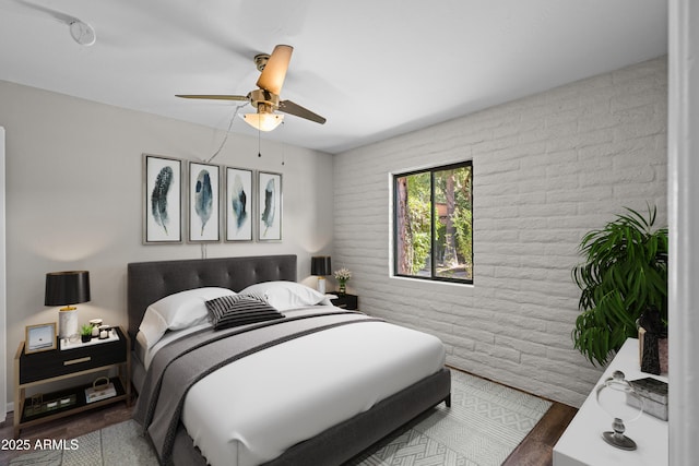 bedroom featuring brick wall, ceiling fan, and wood finished floors