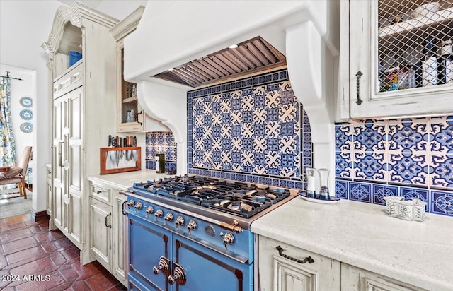 kitchen featuring blue cabinetry, backsplash, premium range hood, and range with gas stovetop