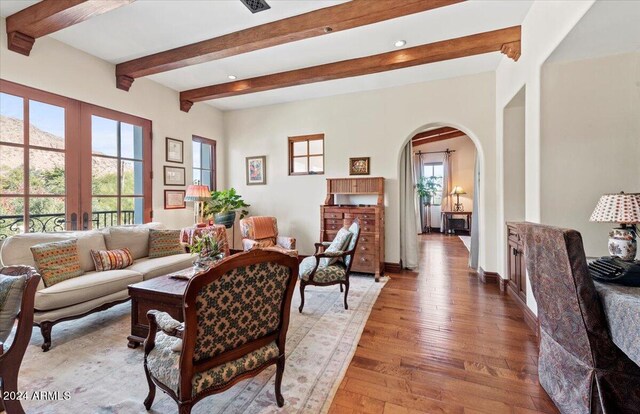 living room featuring light hardwood / wood-style flooring, beamed ceiling, and french doors