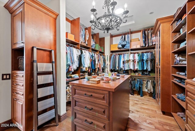 spacious closet with light wood-type flooring and an inviting chandelier