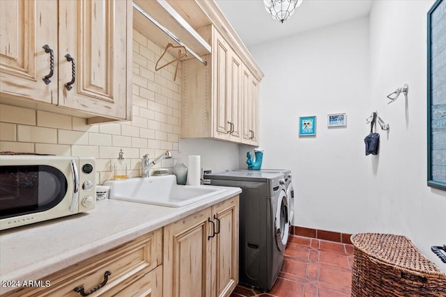 washroom with cabinets, dark tile patterned flooring, washer and clothes dryer, and sink