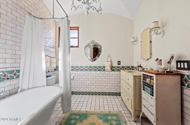 bathroom with vaulted ceiling, tile patterned flooring, vanity, and tile walls