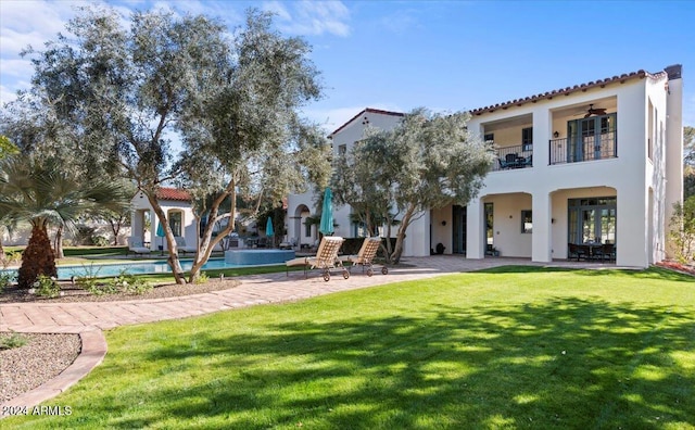 rear view of house with a lawn, a patio area, ceiling fan, and a balcony