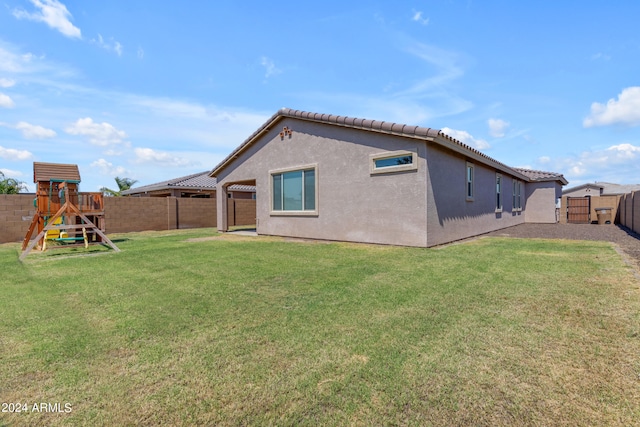 back of house with a playground and a yard