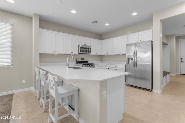 kitchen with kitchen peninsula, sink, a breakfast bar, appliances with stainless steel finishes, and white cabinets