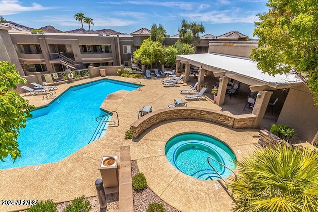 view of swimming pool featuring a patio and a hot tub