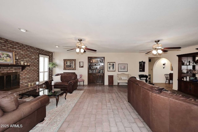 7537 W Bluefield Ave, Glendale, AZ 85308 - living room featuring ceiling fan, a brick fireplace, brick flooring, and arched walkways