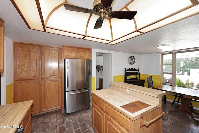 7537 W Bluefield Ave, Glendale, AZ 85308 - kitchen featuring freestanding refrigerator, butcher block countertops, a wood stove, ceiling fan, and a wainscoted wall