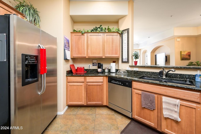 kitchen featuring sink, appliances with stainless steel finishes, and dark stone counters