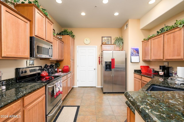 kitchen featuring appliances with stainless steel finishes, light tile patterned floors, and dark stone countertops