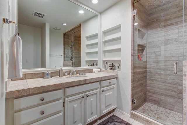 bathroom featuring a shower with shower door and vanity