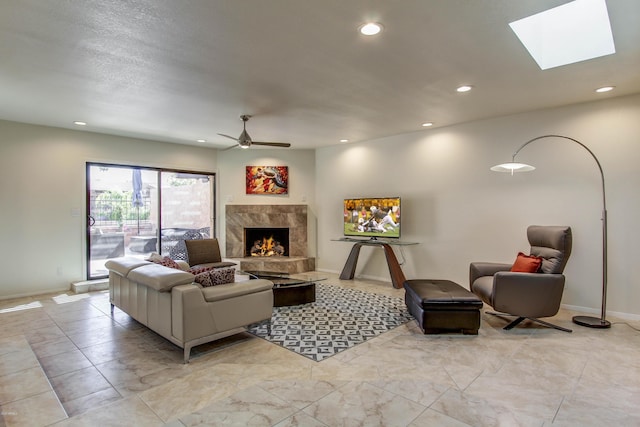 living room with ceiling fan, a skylight, and a fireplace