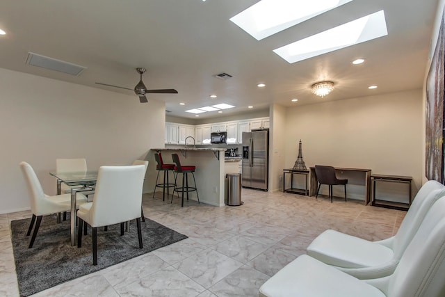 dining area featuring ceiling fan, a skylight, and sink