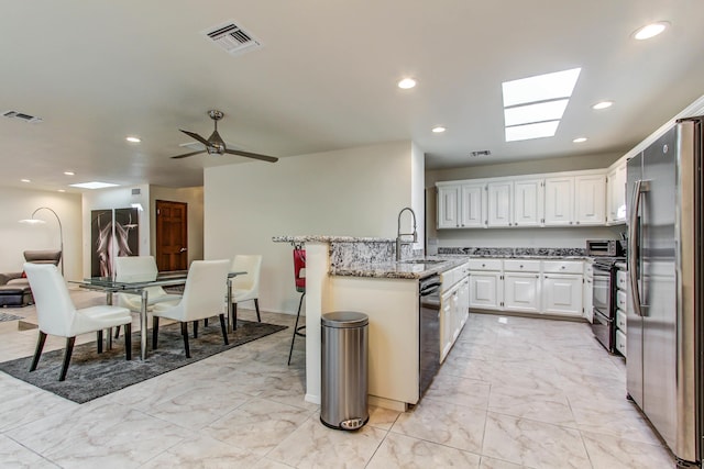 kitchen featuring stove, sink, stainless steel refrigerator, black dishwasher, and white cabinets