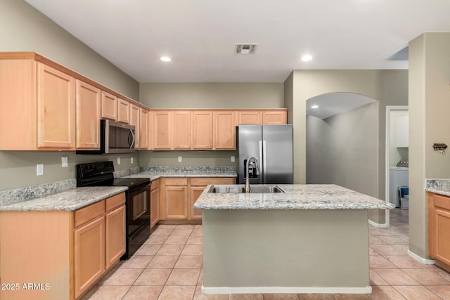 kitchen featuring sink, light brown cabinets, appliances with stainless steel finishes, light stone countertops, and a kitchen island with sink