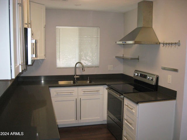 kitchen featuring stainless steel range with electric stovetop, wall chimney exhaust hood, white cabinets, and sink