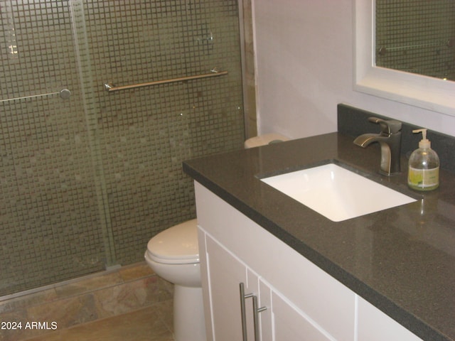 bathroom featuring a shower with door, vanity, and toilet