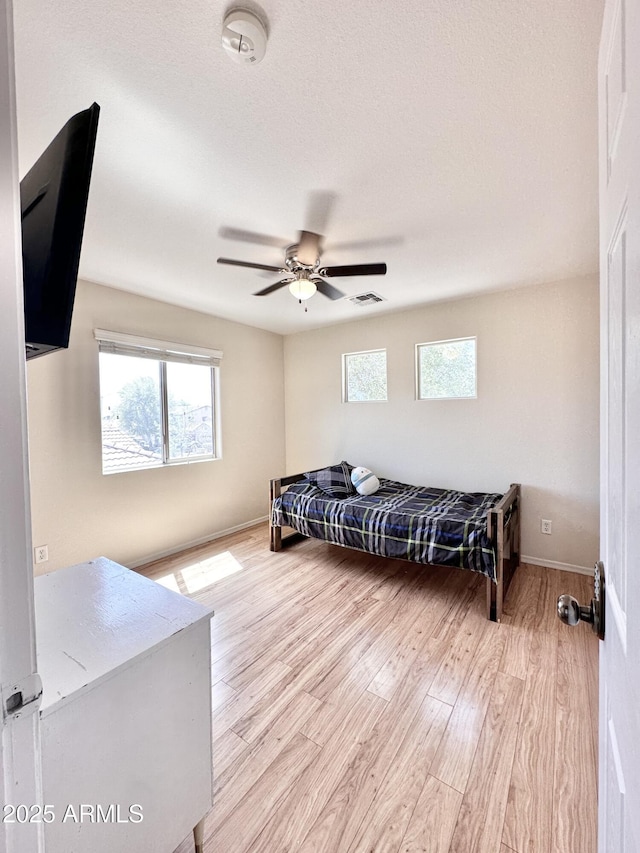 living room featuring a ceiling fan, visible vents, a wealth of natural light, and light wood-type flooring