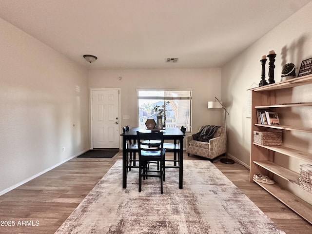 dining area featuring wood finished floors, visible vents, and baseboards
