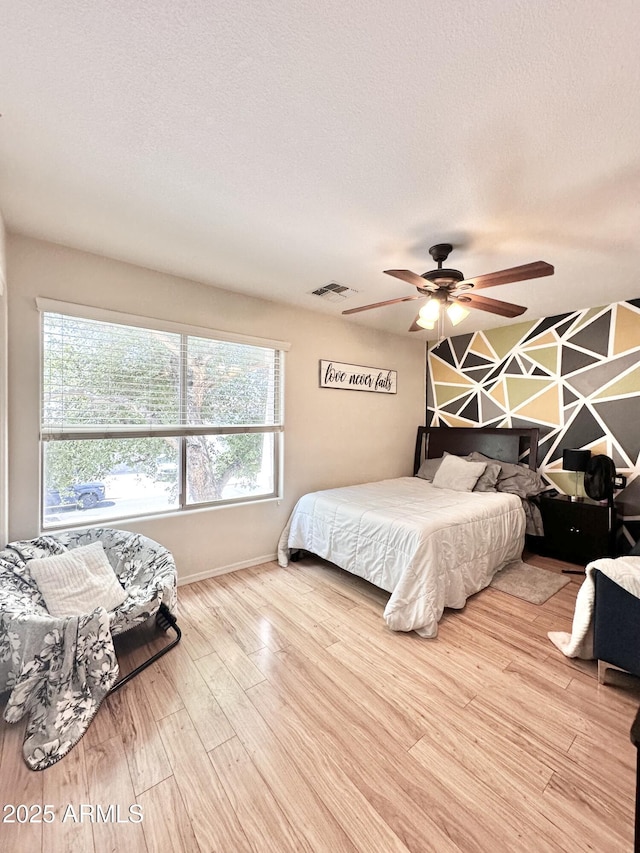 bedroom featuring baseboards, visible vents, wood finished floors, and multiple windows