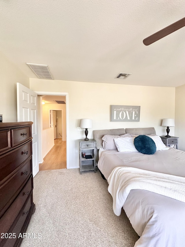 bedroom featuring visible vents, ceiling fan, and light carpet