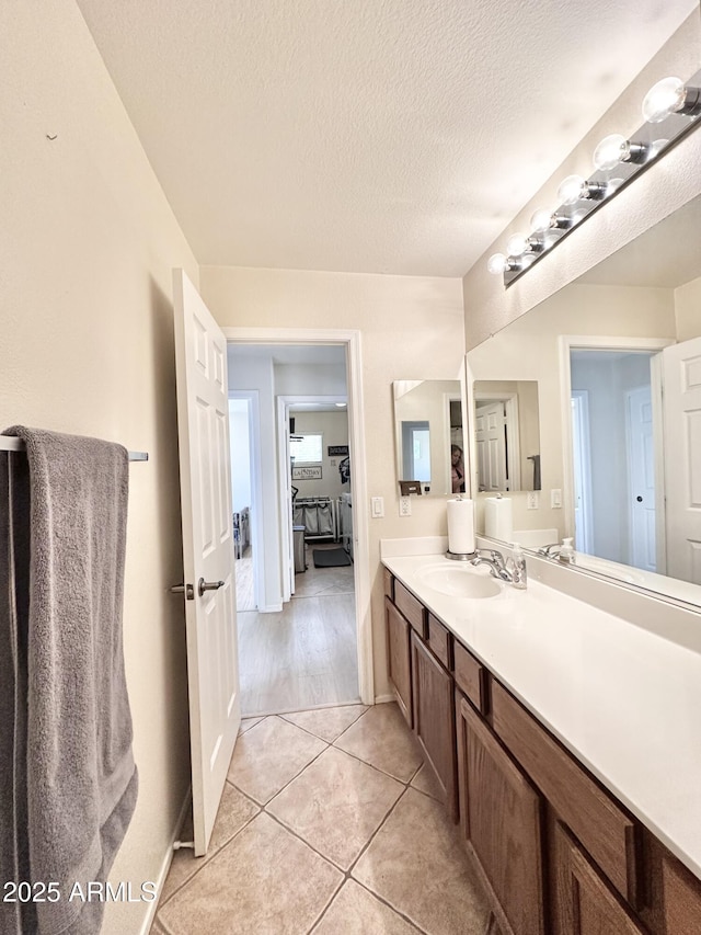 bathroom with a textured ceiling, tile patterned flooring, and vanity