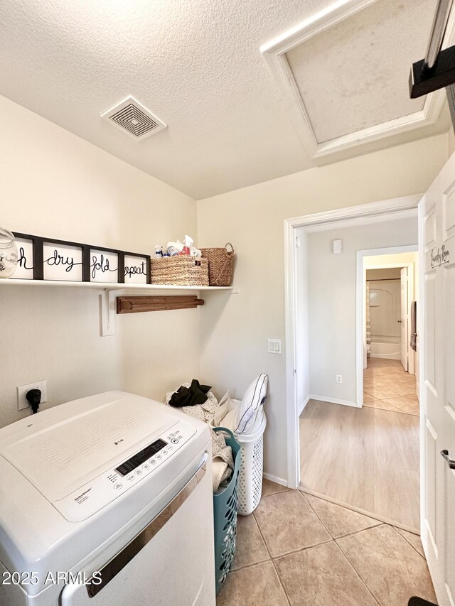 laundry room featuring laundry area, light tile patterned floors, attic access, visible vents, and a textured ceiling