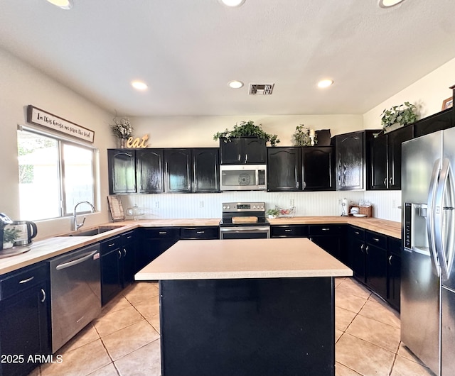 kitchen with light tile patterned floors, a sink, stainless steel appliances, and light countertops