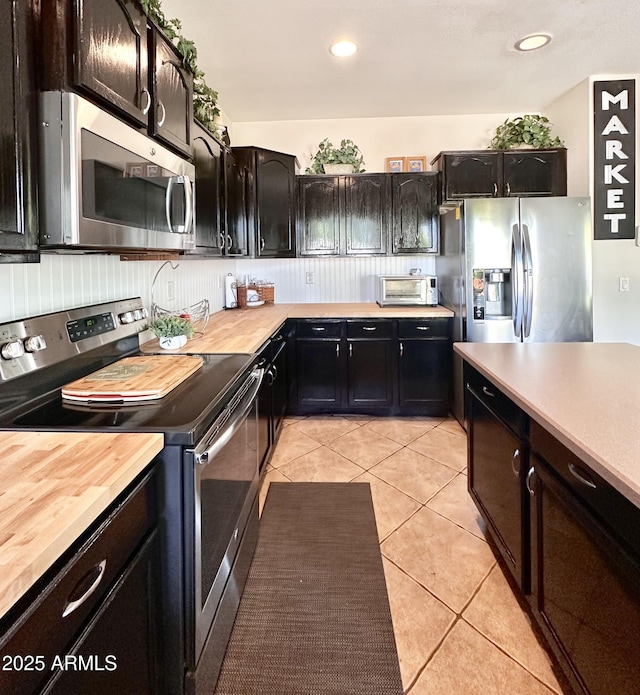 kitchen featuring light tile patterned flooring, butcher block countertops, stainless steel appliances, and recessed lighting