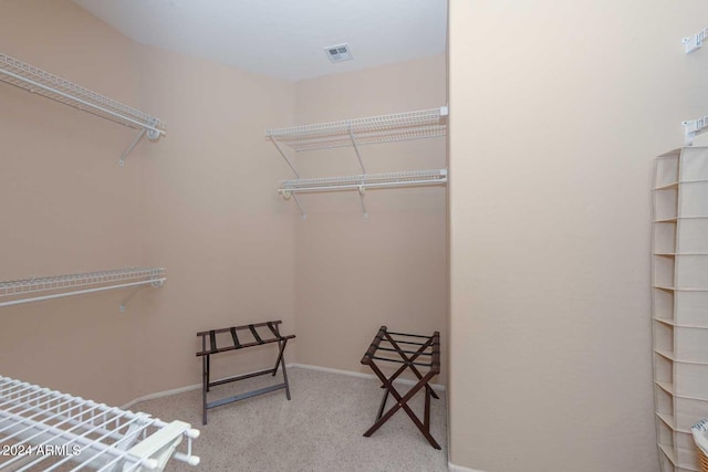 walk in closet featuring light colored carpet