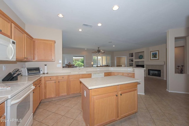 kitchen with light brown cabinets, kitchen peninsula, white appliances, and light tile patterned floors