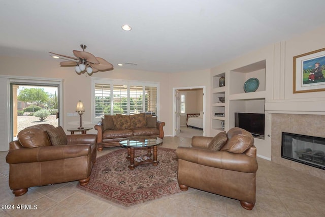 living room featuring light tile patterned floors, a tile fireplace, plenty of natural light, and built in shelves