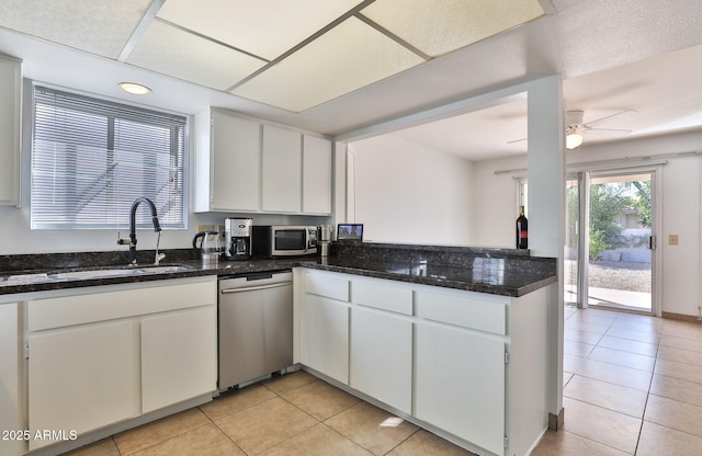 kitchen featuring white cabinets, ceiling fan, appliances with stainless steel finishes, a sink, and light tile patterned flooring