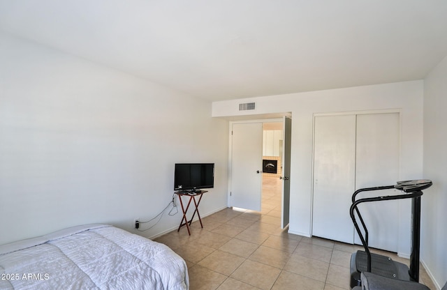 bedroom with a closet, light tile patterned flooring, and visible vents