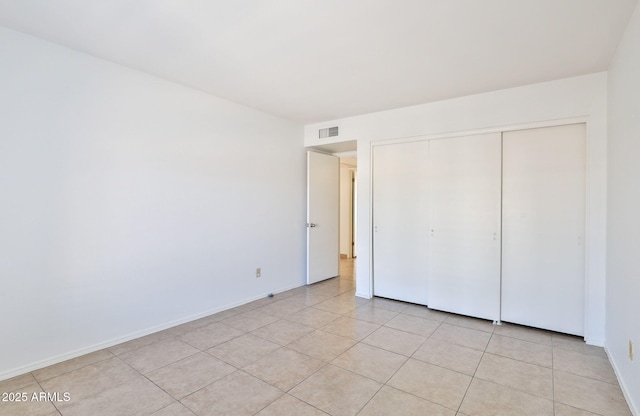 unfurnished bedroom featuring light tile patterned floors, baseboards, visible vents, and a closet