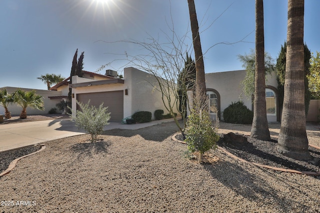 view of front facade featuring concrete driveway, an attached garage, and stucco siding