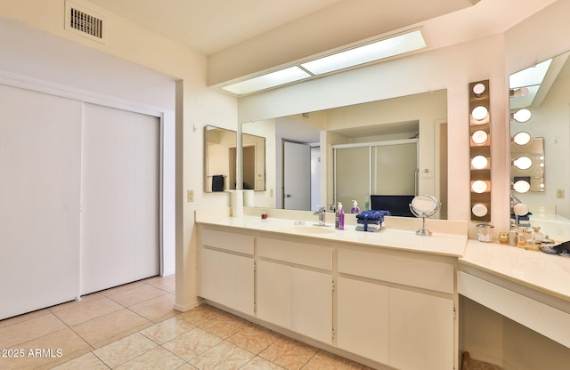 full bathroom featuring a skylight, visible vents, vanity, a shower stall, and tile patterned flooring