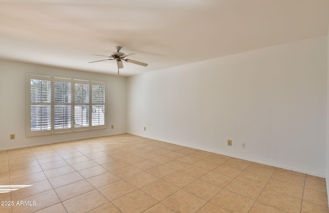 empty room with light tile patterned flooring, a ceiling fan, and baseboards