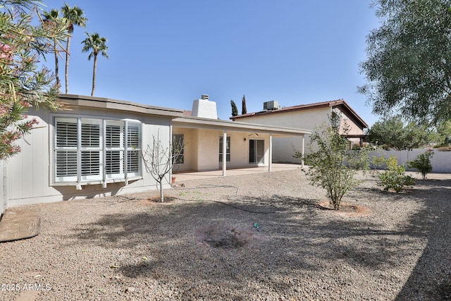 back of property with a patio, a chimney, and fence