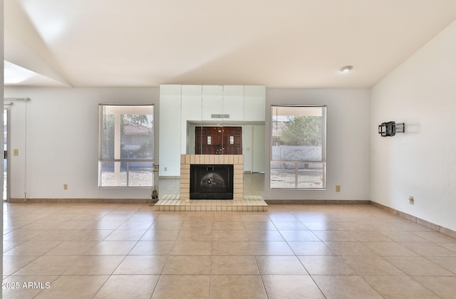 unfurnished living room featuring light tile patterned flooring, visible vents, baseboards, vaulted ceiling, and a brick fireplace