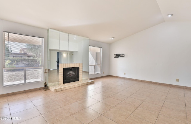 unfurnished living room featuring a fireplace with raised hearth, vaulted ceiling, baseboards, and light tile patterned floors