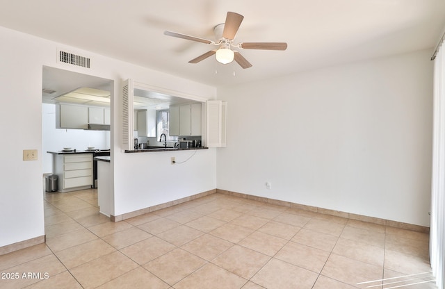 kitchen with light tile patterned floors, dark countertops, visible vents, ceiling fan, and baseboards